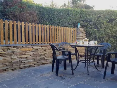 a table and chairs sitting on a patio with a fence at Heightley House in Tintagel