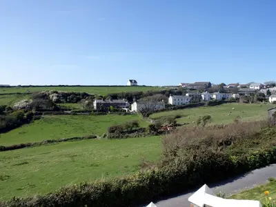 a view of a green field with houses and a river at Heightley House in Tintagel