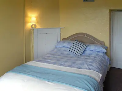 a bed with a blue and white striped pillow on it at Tresungers Cottage in Port Isaac