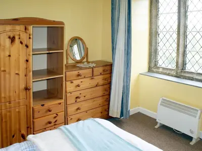 a bedroom with a wooden dresser and a mirror at Tresungers Cottage in Port Isaac