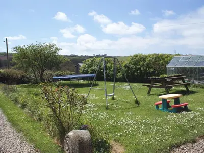 a playground with a picnic table and a swing at Tresungers Cottage in Port Isaac