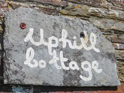 a sign on the side of a brick wall at Uphill Cottage in Saint Ervan