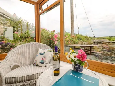 a table with a bottle of wine and a glass at Uphill Cottage in Saint Ervan