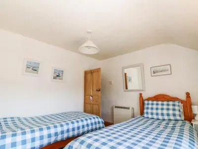 two beds in a room with white walls at Uphill Cottage in Saint Ervan