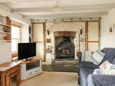 a living room with a fireplace with a couch and a tv at Uphill Cottage in Saint Ervan