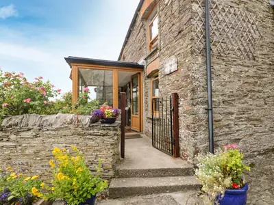 a brick house with a gate and flowers at Uphill Cottage in Saint Ervan