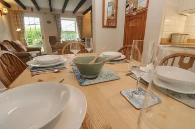 a wooden table with plates and wine glasses on it at Primrose Cottage in Wadebridge