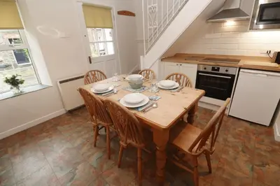 a kitchen with a wooden table and chairs at Primrose Cottage in Wadebridge