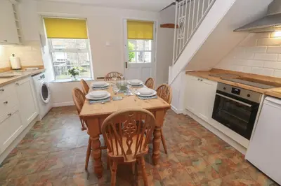 a kitchen with a wooden table and chairs in a room at Primrose Cottage in Wadebridge