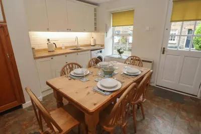 a kitchen with a wooden table and chairs at Primrose Cottage in Wadebridge