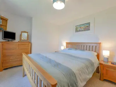 a bedroom with a bed and a dresser and a tv at Primrose Cottage in Wadebridge
