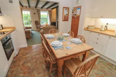 a kitchen and dining room with a wooden table and chairs at Primrose Cottage in Wadebridge