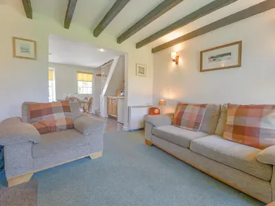 a living room with two couches and a table at Primrose Cottage in Wadebridge