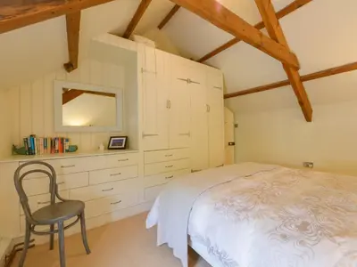 a bedroom with a white bed and a chair at 3 Newhall Green in Delabole
