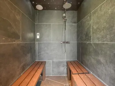 a shower with a wooden bench in a bathroom at 3 Newhall Green in Delabole