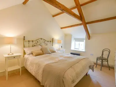 a bedroom with a large bed and a chair at 3 Newhall Green in Delabole