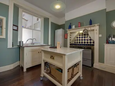 a kitchen with green walls and a counter with a refrigerator at The Captains House in Downderry