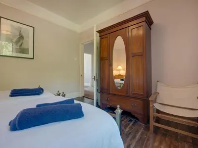a bedroom with two beds and a dresser and a mirror at The Captains House in Downderry
