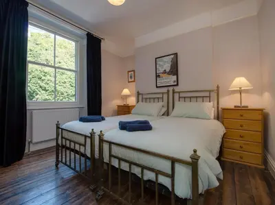 a bedroom with a large bed with two blue pillows on it at The Captains House in Downderry