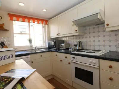 a kitchen with white cabinets and a stove top oven at Pier Cottage in Saint Mawes