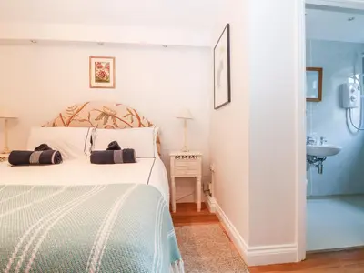 a white bedroom with a bed and a sink at Pier Cottage in Saint Mawes