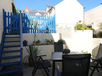 a patio with a blue fence and chairs at Pier Cottage in Saint Mawes