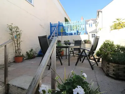 a patio with a table and chairs and a fence at Pier Cottage in Saint Mawes