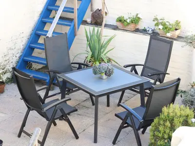 a table and chairs on a patio with a ladder at Pier Cottage in Saint Mawes