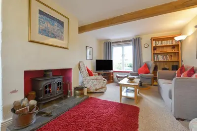 a living room with a fireplace and a red rug at Regatta Cottage in Feock