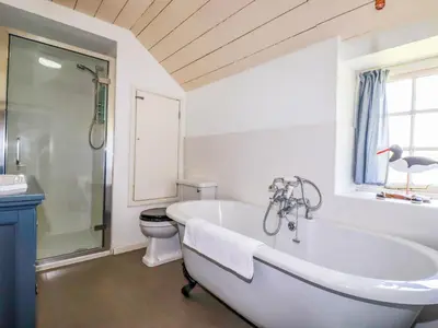 a white bathroom with a tub and a toilet at Polcreek Farmhouse in Veryan