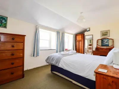 a bedroom with a bed and a dresser and window at Polcreek Farmhouse in Veryan