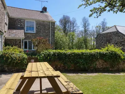 a wooden picnic table in front of a house at Polcreek Farmhouse in Veryan