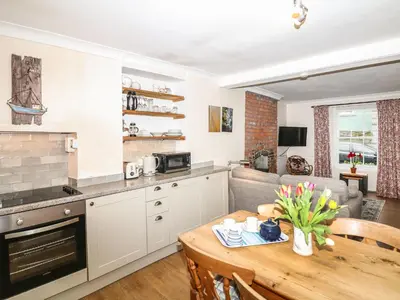 a kitchen and living room with a table and a couch at Quarry Cottage in Flushing