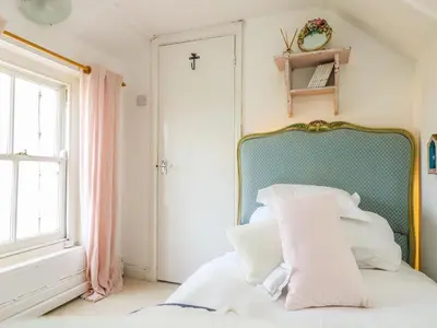 a bedroom with a bed with white pillows and a window at Evergreen in Breage