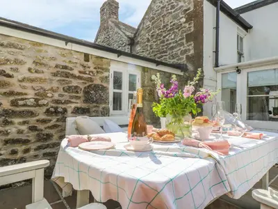 a table with food and flowers on a patio at Evergreen in Breage