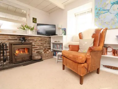 a living room with a chair and a fireplace at Evergreen in Breage