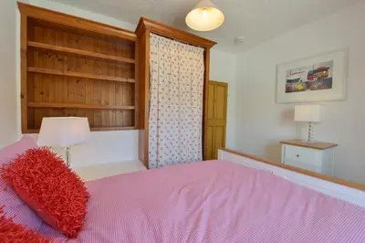 a bedroom with a pink bed with a red pillow at April Cottage in Coverack