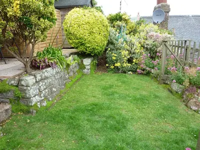 a garden with a stone wall and some flowers at April Cottage in Coverack