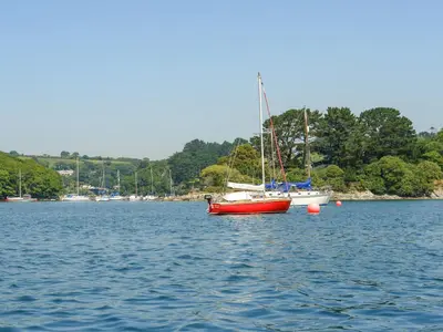 a red boat sitting in the middle of a body of water at 2 Trerise Cottage in Helford
