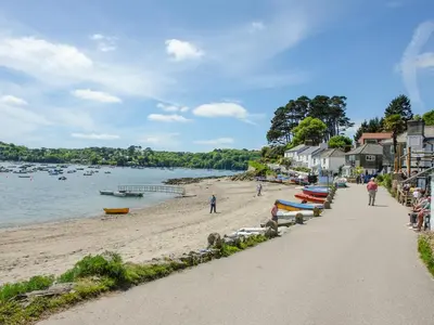 a beach with people and boats on the sand at 2 Trerise Cottage in Helford