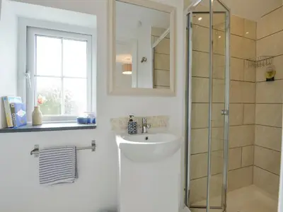a bathroom with a shower and a sink and a mirror at 2 Trerise Cottage in Helford