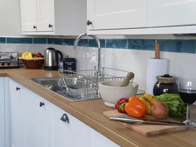 a kitchen counter with vegetables on a cutting board and a sink at The Studio in Germoe