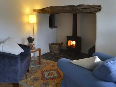 a living room with a fireplace and a blue couch at The Studio in Germoe