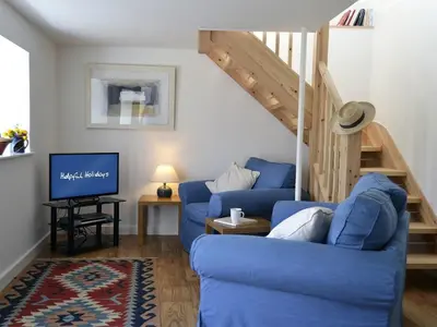 a living room with two blue couches and a staircase at The Studio in Germoe