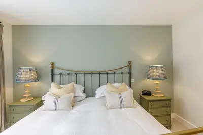 a bedroom with a large white bed with two lamps at Trewornan Manor in Wadebridge