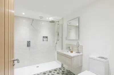 a white bathroom with a shower and a sink at Trewornan Manor in Wadebridge