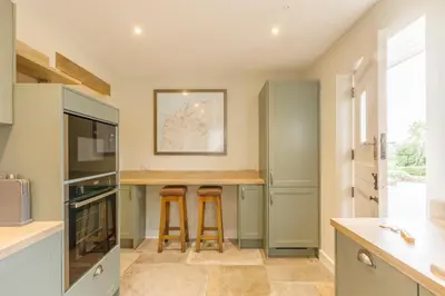 a kitchen with green cabinets and a counter with stools at Trewornan Manor in Wadebridge