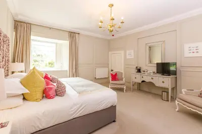 a bedroom with a bed and a desk and a television at Trewornan Manor in Wadebridge