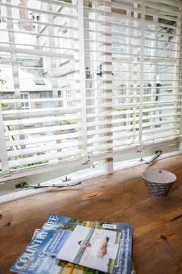 a window with white shutters and a book on a table at Trewornan Manor in Wadebridge