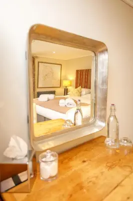 a mirror on a table with a bed in a room at Trewornan Manor in Wadebridge
